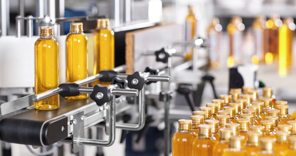 Production line of beauty and healthcare products at plant or factory. Process of manufacturing and packaging cosmetics goods. Glass or plastic bottles with screw caps standing on conveyor belt
